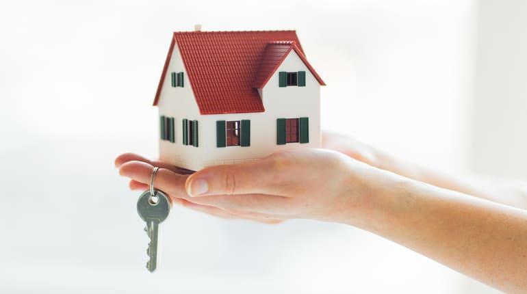deux mains tenants une maison avec des clés